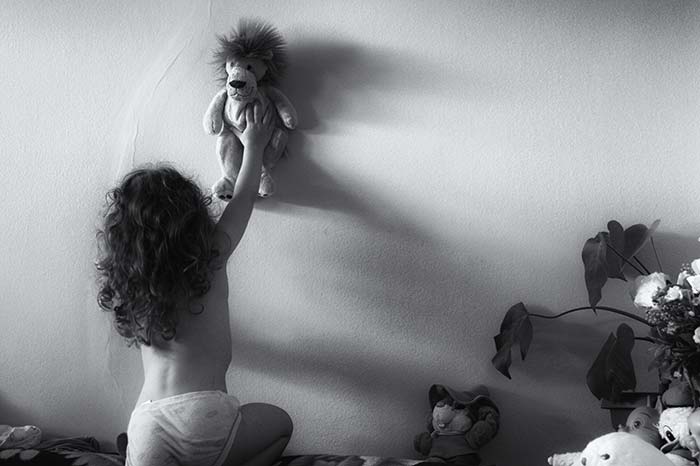 Girl with Lion Toy on Wall | Djevojčica stavlja svog lava-igračku na zid