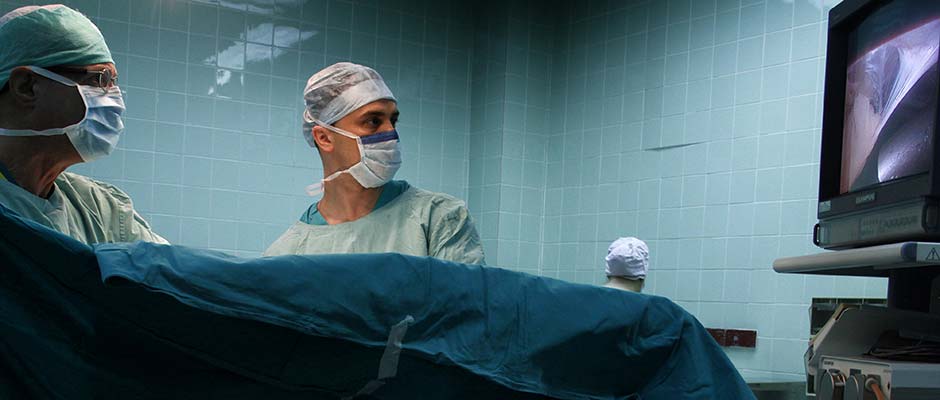 Hirurzi gledaju monitor na kojem se putem laparoskopa prikazuju unutrašnji organi pacijenta | Surgeons Check a Monitor Showing the Internal View Through the Laparoscope