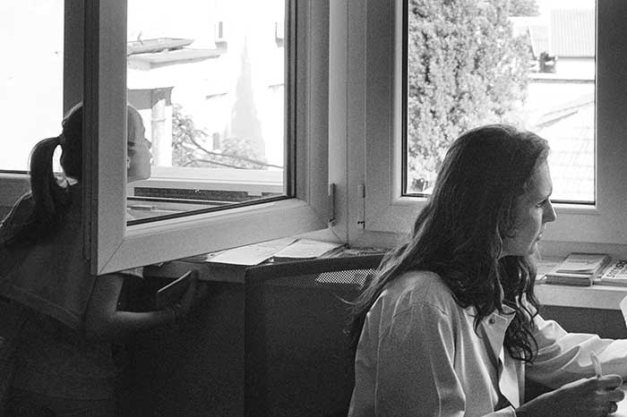 A little girl looks out the window of the examination room while Dr. Paulina Miletic-Simic works. | Mlada jevojčica gleda kroz prozor ordinacije dok Dr. Paulina Miletić-Simić radi.